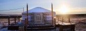 Buryat yurt is installed on decking floor in steppe by fence